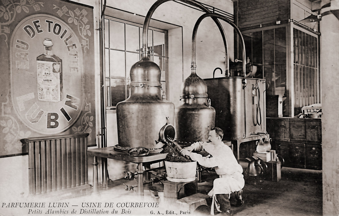 Atelier de distillation de l'usine de Courbevoie : un ouvrier en blouse blanche s'affaire devant deux grands alambics de cuivre, sous un panneau mural à l'enseigne Eau de Toilette Lubin.